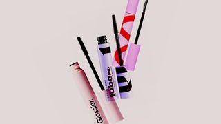A collage of Glossier Urban Decay and Tower 28 mascaras on a light gray background