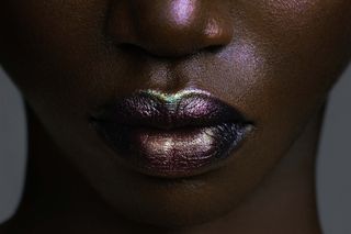 Close up of model with green and purple iridescent makeup