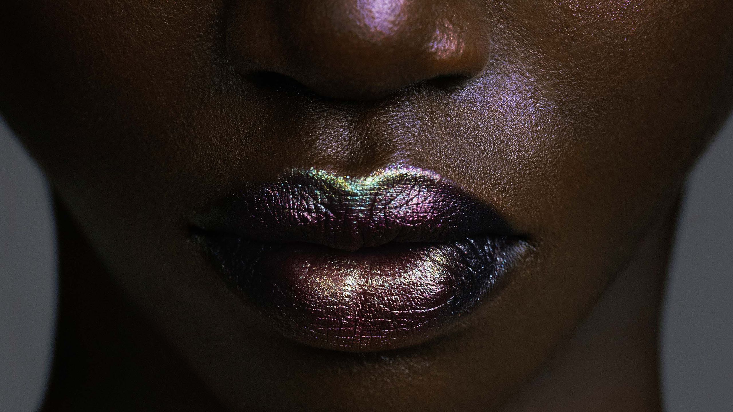 Close up of model with green and purple iridescent makeup