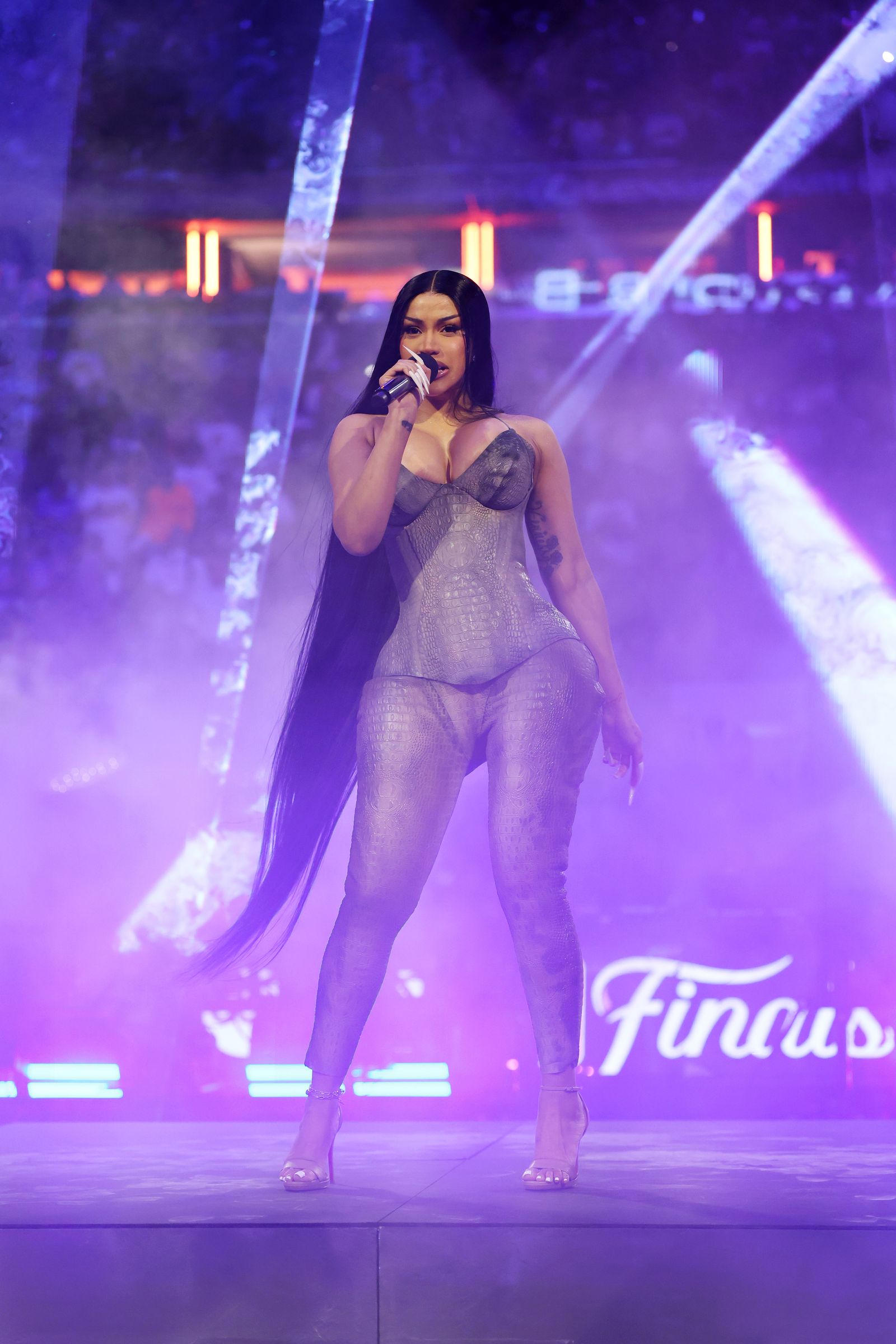Cardi B performs at the NBA Game 3 game at Madison Square Garden. She wears a catsuit and long calflength hair.