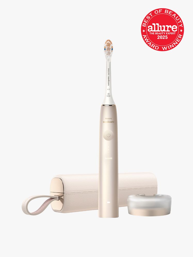 Philips Sonicare 9900 Prestige in branded gold and white color way with matching travel case and stand on light gray...