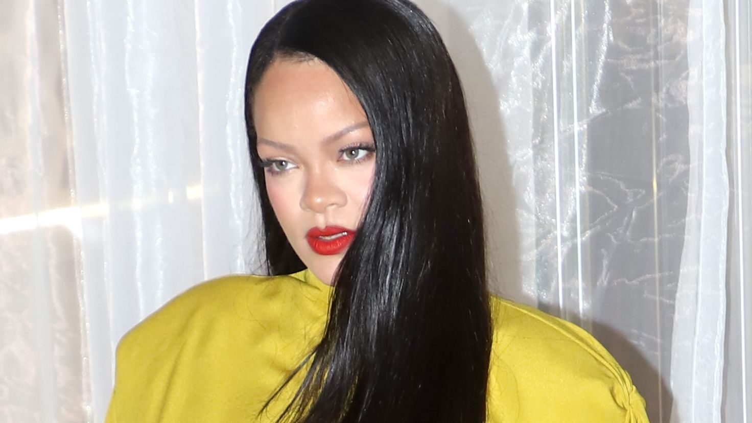 Rihanna posing with long straight hair and a chartreuse top